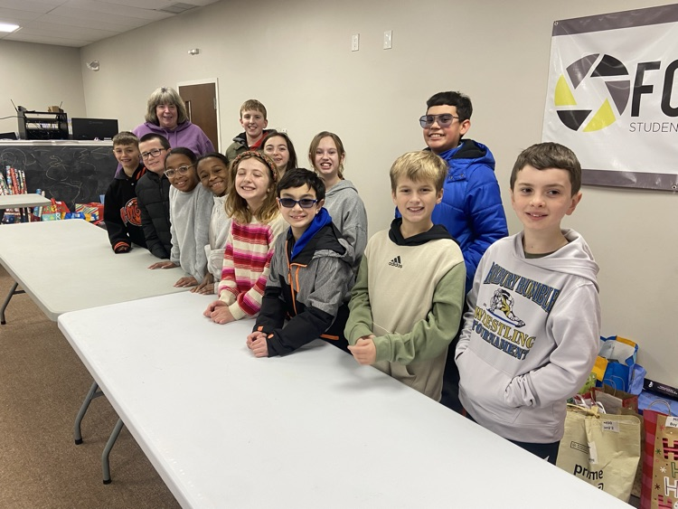 .Female and Male 4th grade students with an adult female . All 12 students  and Female adult volunteer posing at a table all smiles
