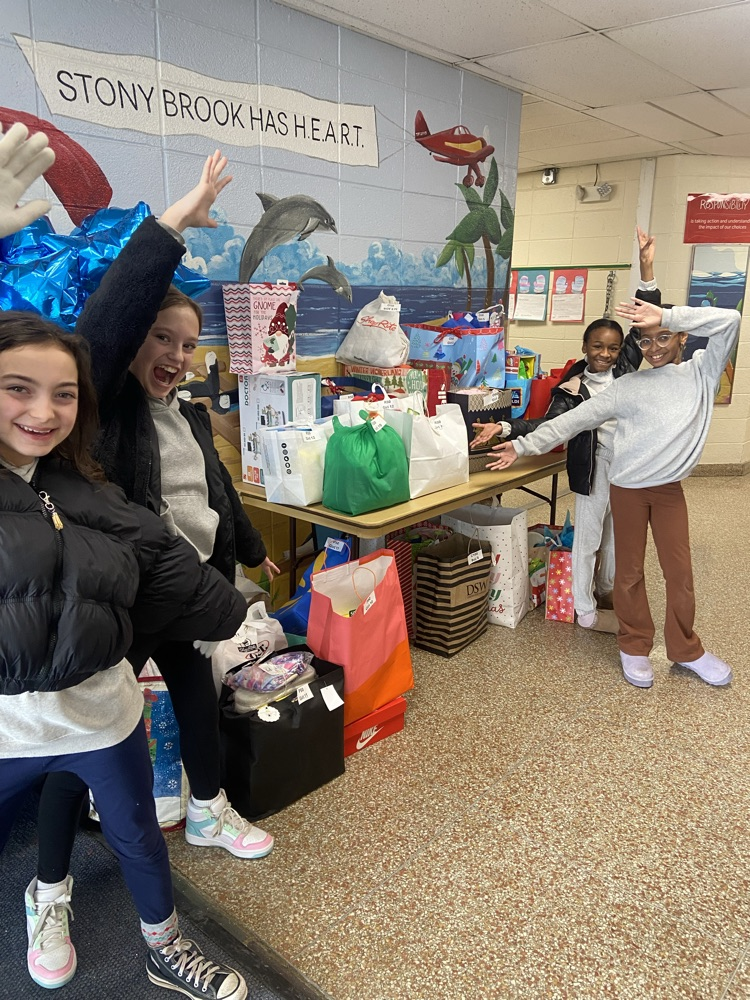 .4 female students posing happily with the giving tree donations  