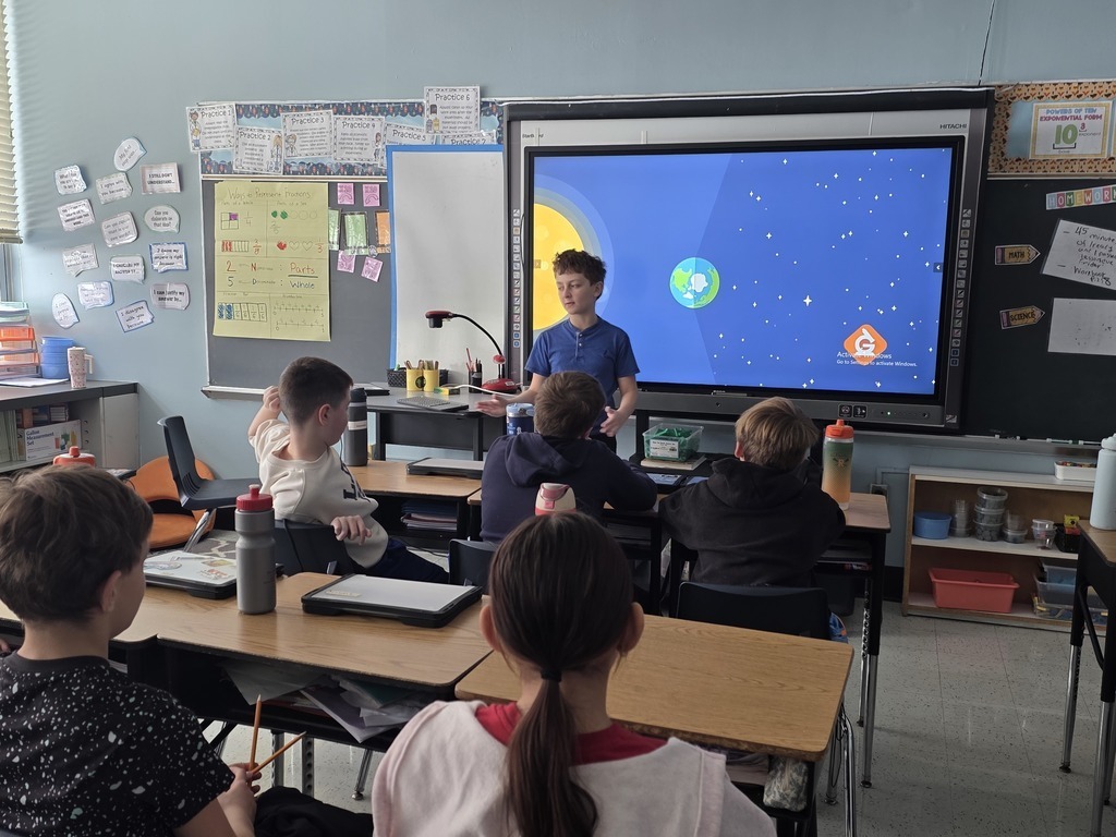 students in their classroom chairs looking at one students presenting - regular day at our Home Away from Home...