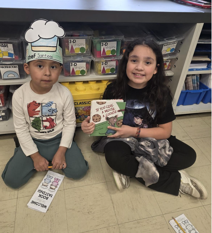 2 students reading and posing with their book