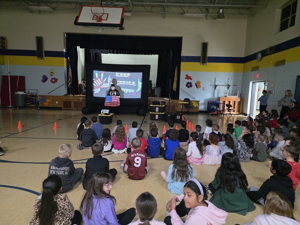 Students sitting on the floor, looking forward to the presenter. The Illusion Maker is here teaching our Birchwood Buddies how to Reduce, Reuse and Recycle.