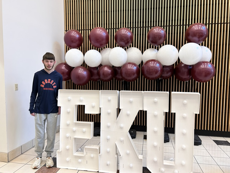 A student stands next to a large size EKU sign  