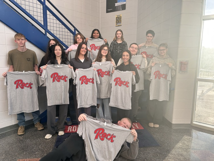 Students stand holding up t-shirts that read Rock