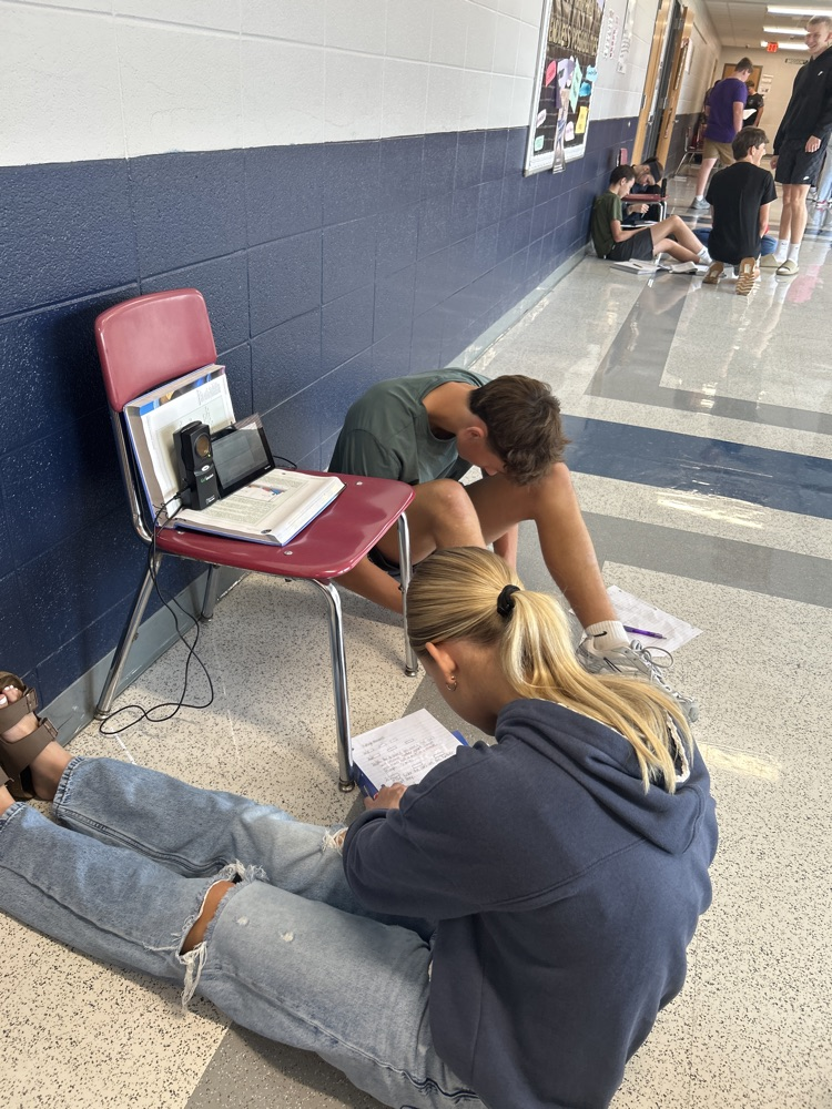 Students sit in the school hallway.