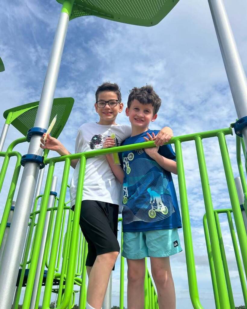 Two students on a playscape standing together and smiling.