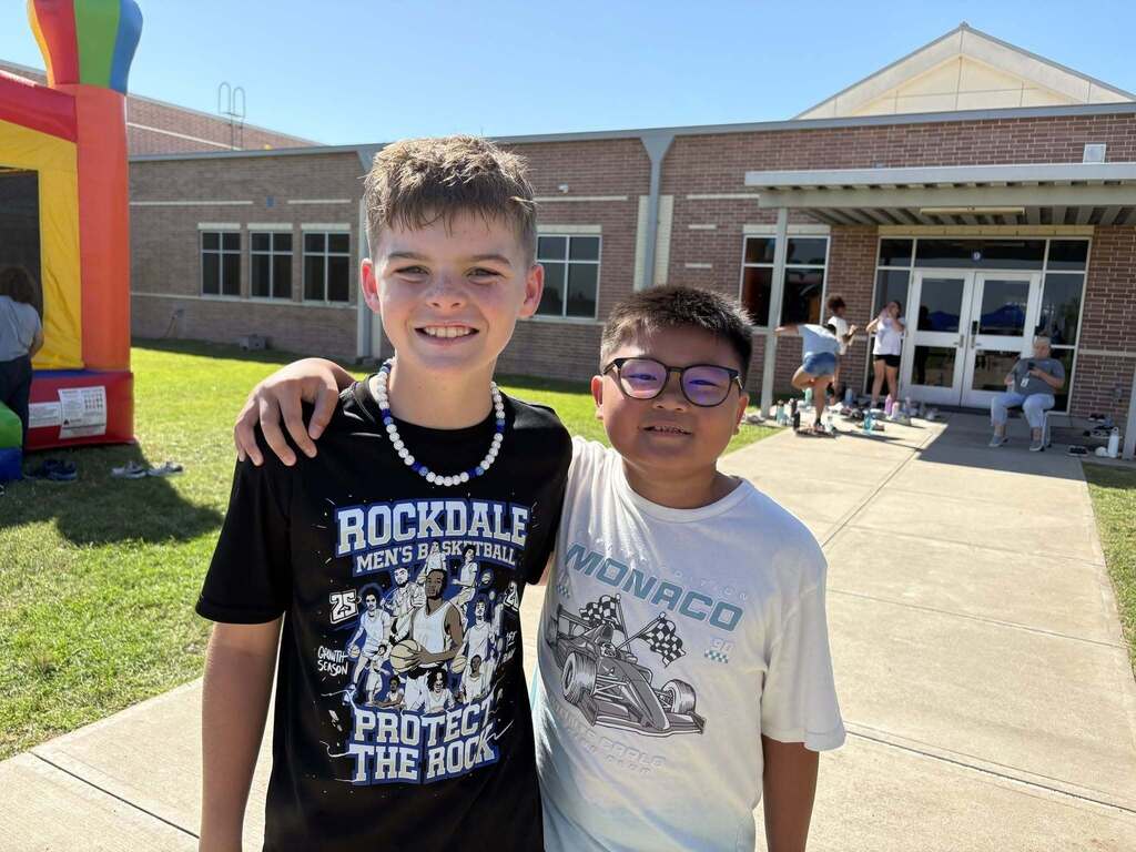 Two boys standing together and smiling.