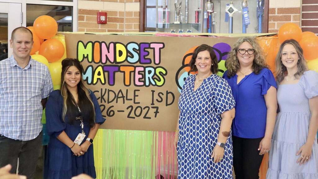 A group of people smiling in front of a sign that says "Mindset Matters"