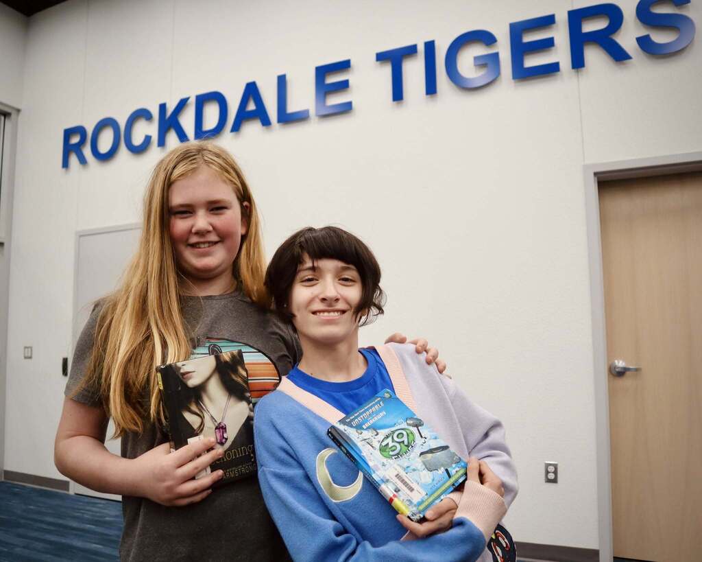 two students standing together holding books