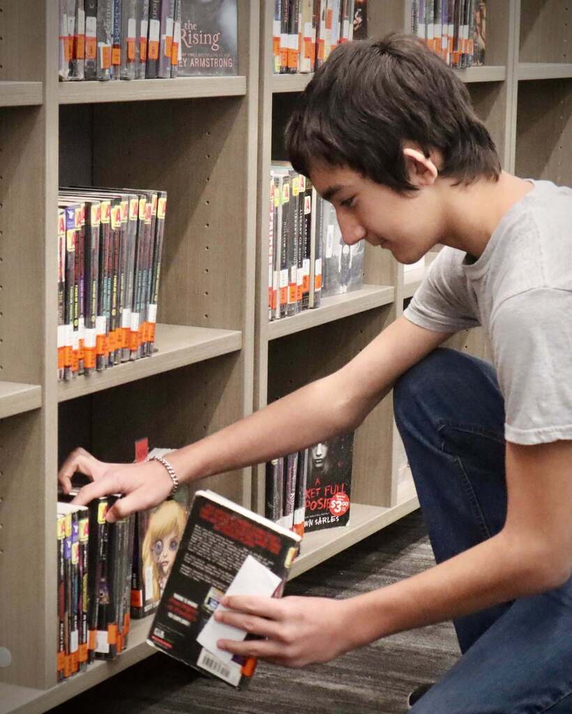 Junior high student looking through books at the library