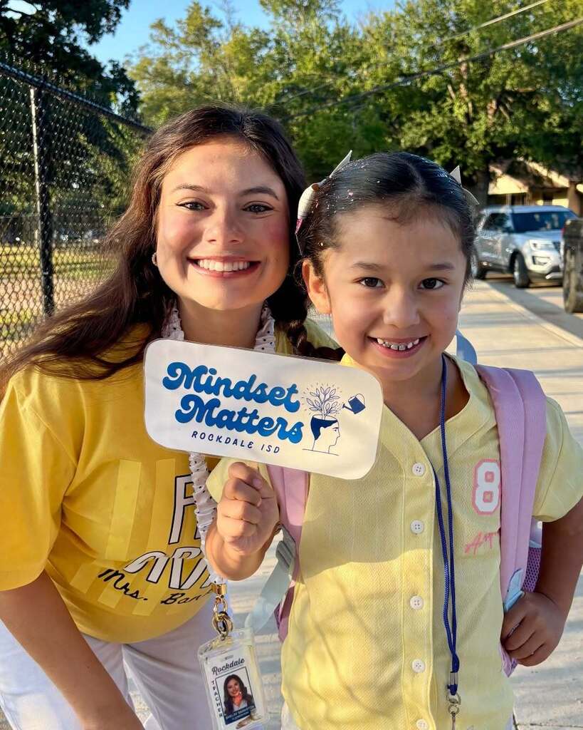 Smiling woman standing with an elementary student who is holding a sign that says mindset matters.