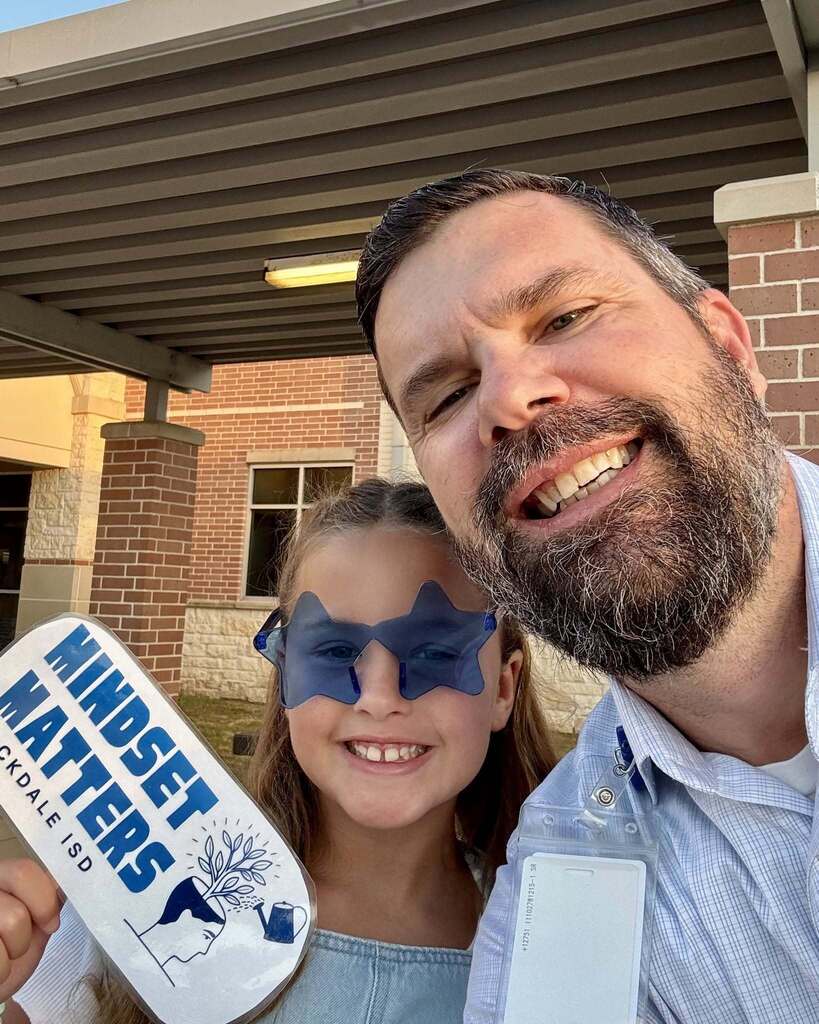 Man smiling with intermediate student who is wearing star sunglasses holding a sign that says mindset matters