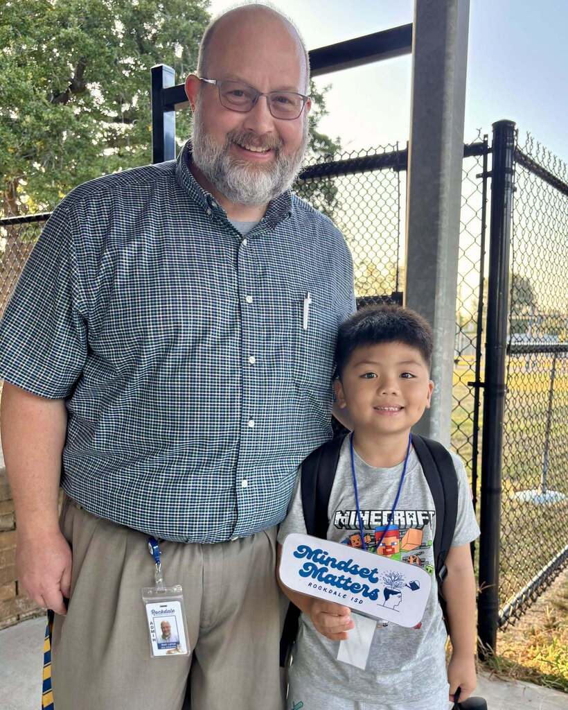 Man smiling with elementary student who is holding a sign that says mindset matters