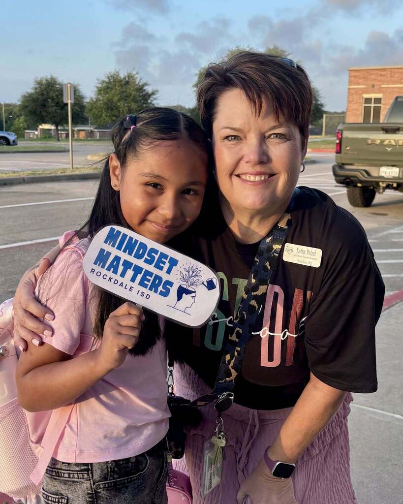 Smiling woman standing with an intermediate student who is holding a sign that says mindset matters.