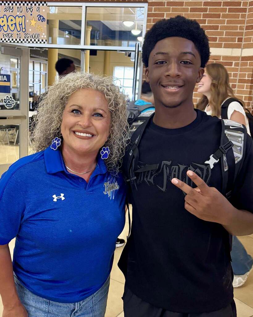 Principal and high school student standing together smiling