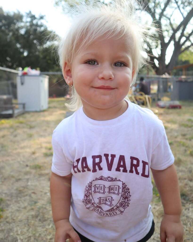 Child in Harvard shirt standing and smiling