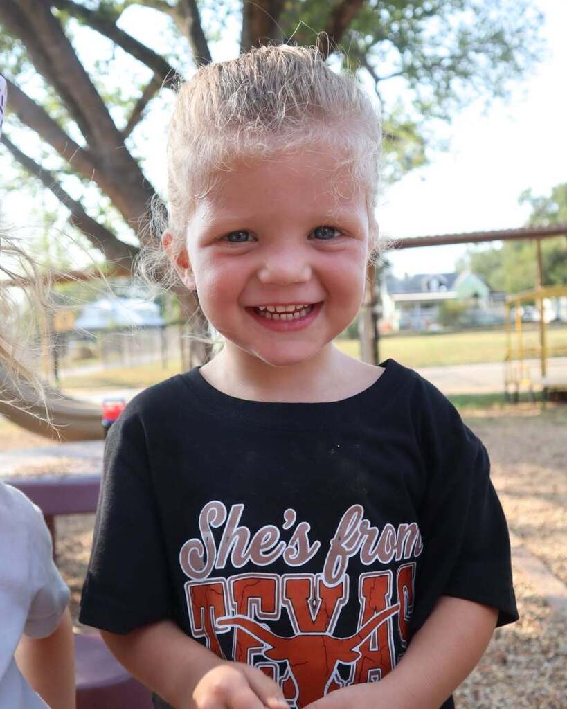Child in University of Texas shirt standing and smiling.