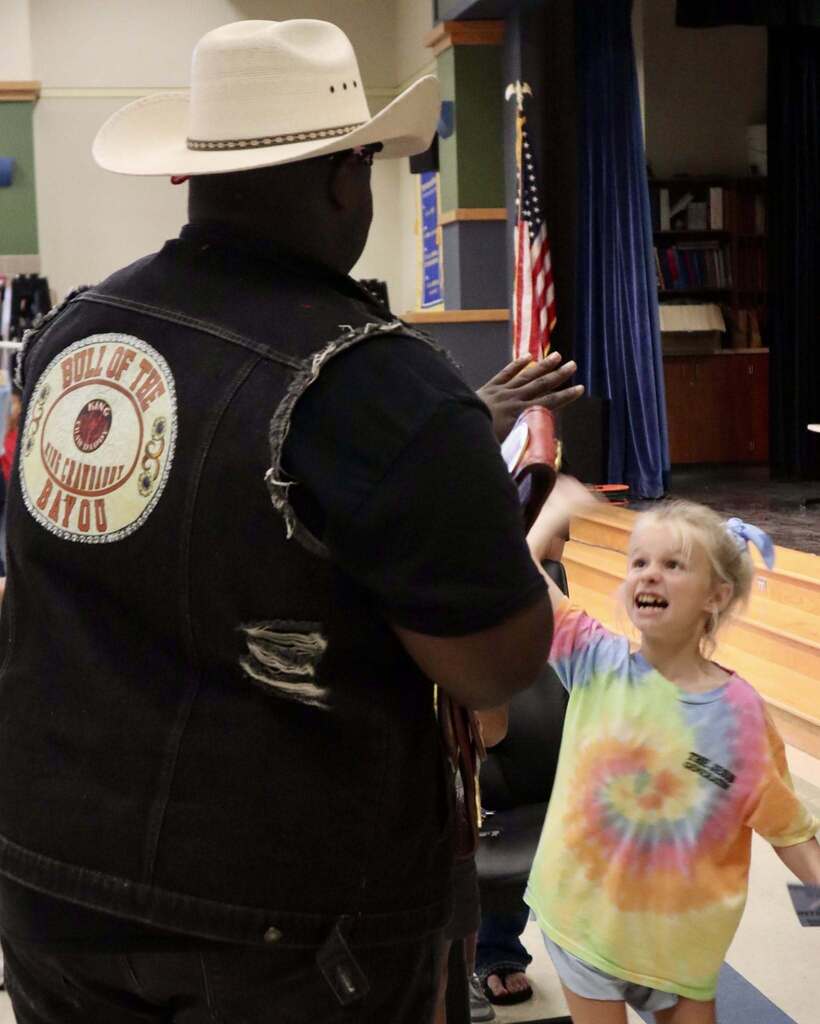 Student hi-fiving a pro wrestler in a cowboy hat.