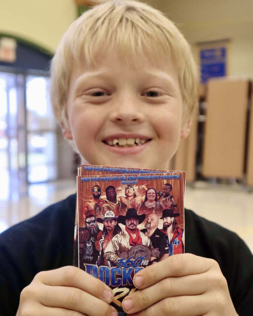 Student with blonde hair holding wrestling tickets
