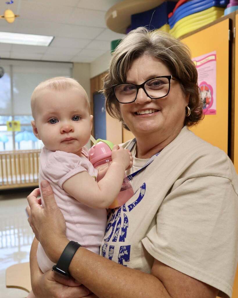 Woman holding a baby and smiling.