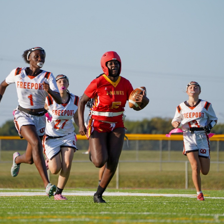 “Jefferson’s Rayniah Johnson (#5) sprints down the field with the ball, pursued by three Freeport defenders during the first flag football game on the new turf.”
