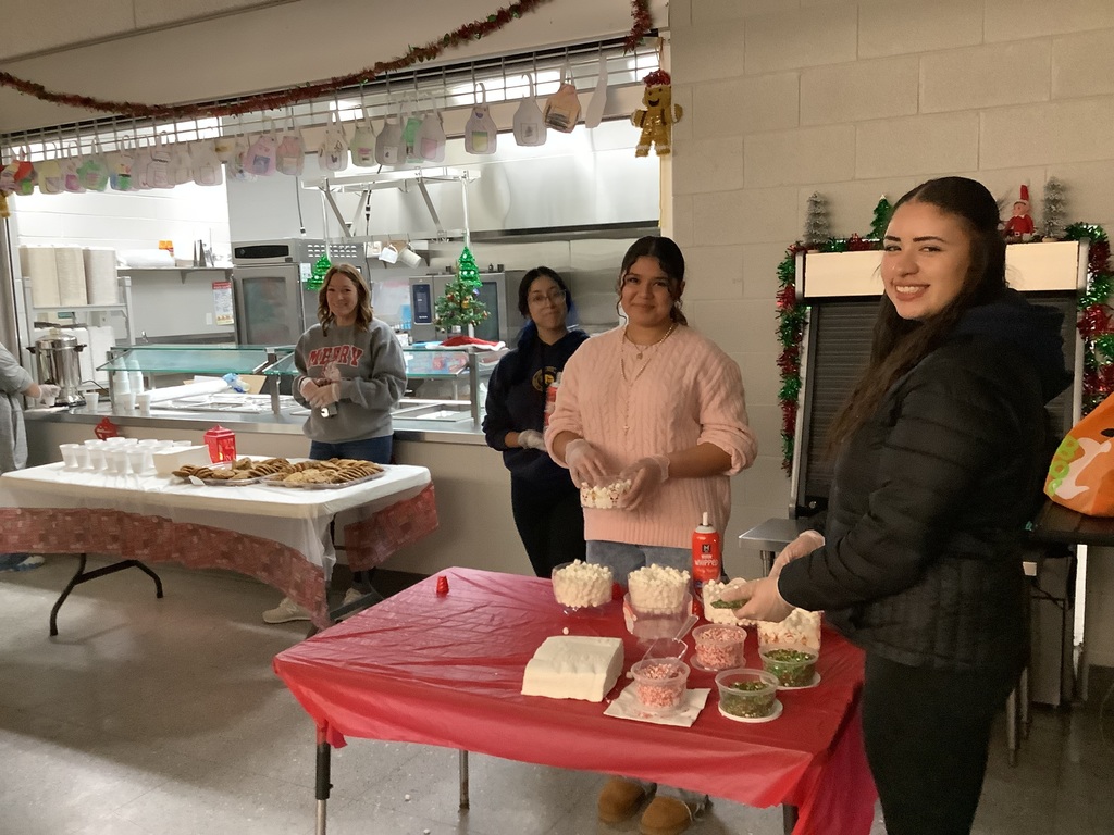Student volunteers and a women serving cookies.