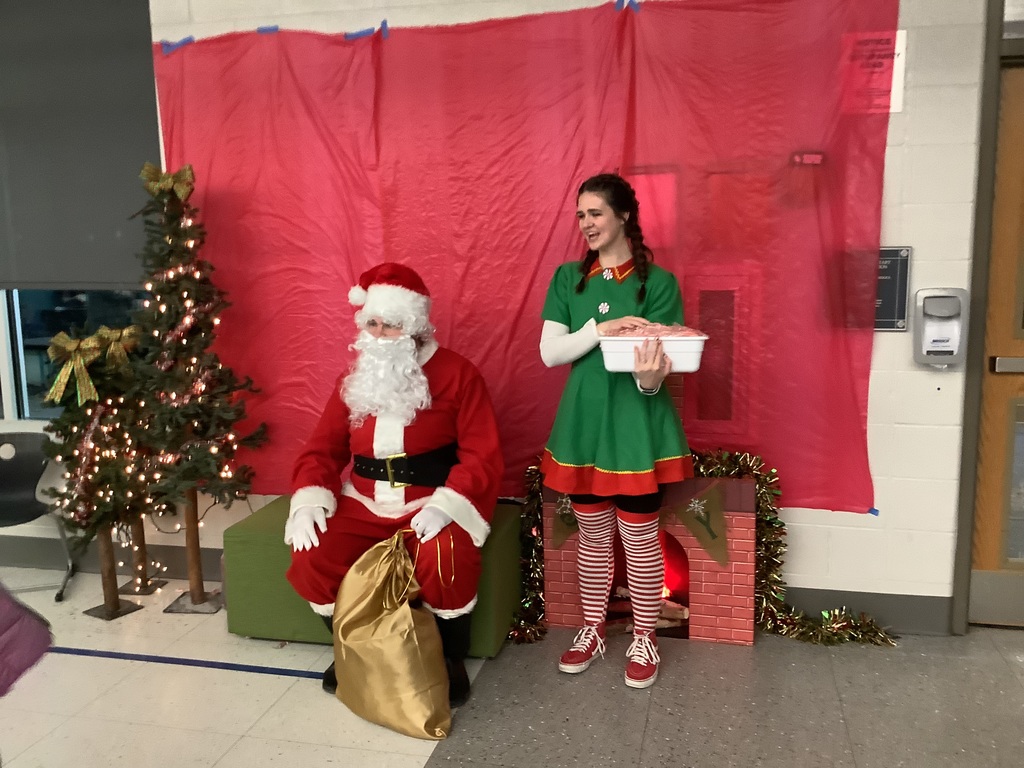 Man dressed as Santa with his elf helper.