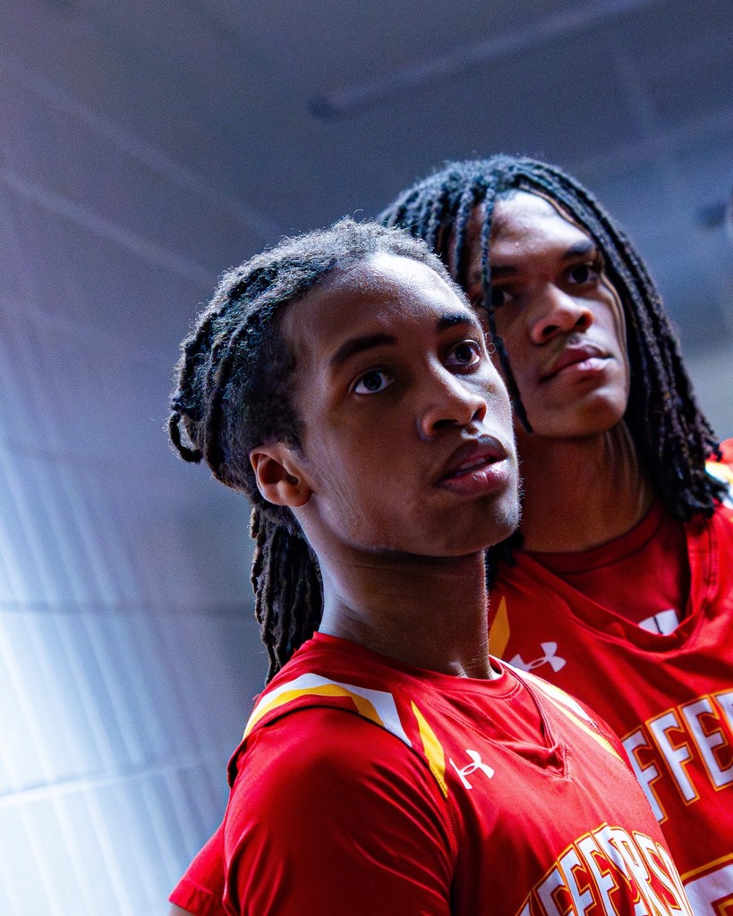 Two basketball students stand next to each looking off screen.