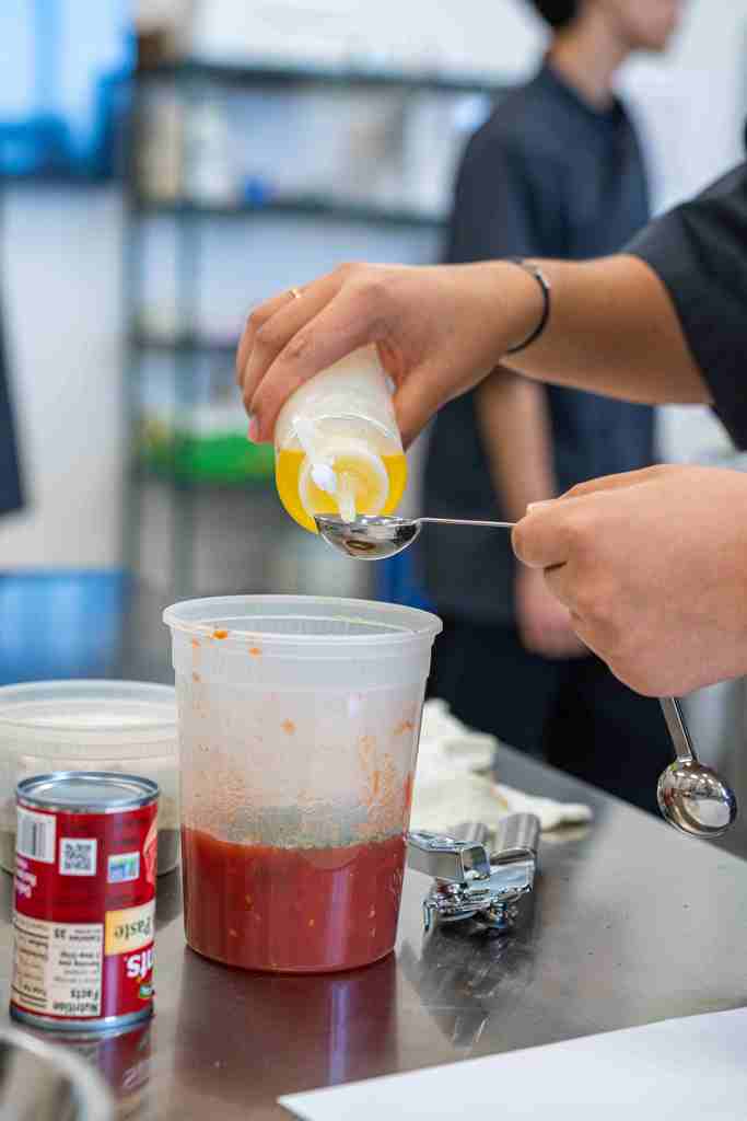 A yellow liquid being measure with a table spoon.