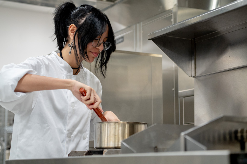 One student is cooking over a stovetop.
