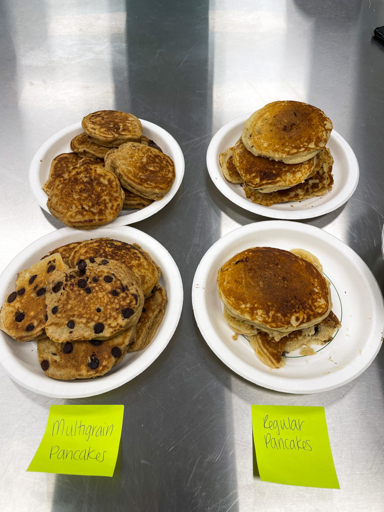 A plate of multigrain pancakes and another plate of regular pancakes.