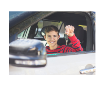 Teenage boy holding keys up in the drivers seat of a car 