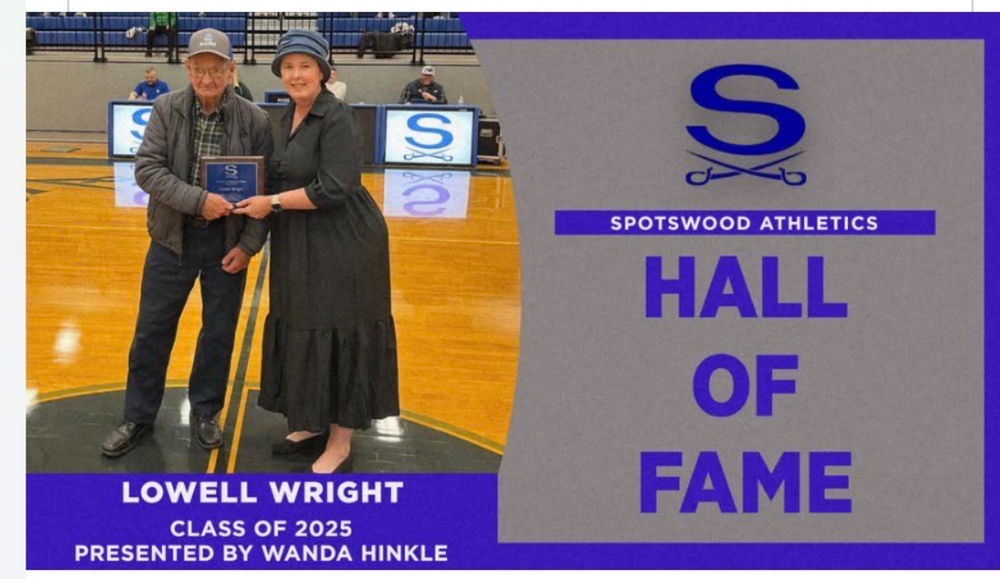 A man holding an award standing next to a woman both people wearing hats