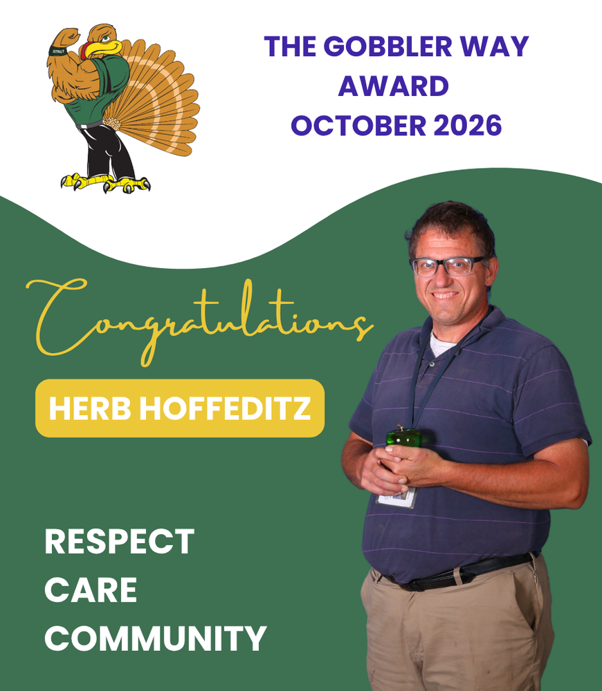 Teacher holds green apple trophy.