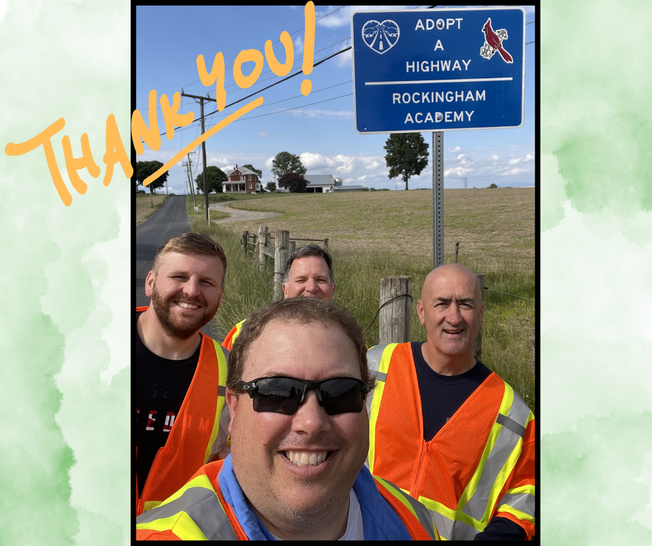 Four men wearing safety vests smile for a photo against a rural backdrop. A blue "Adopt a Highway" sign is visible.