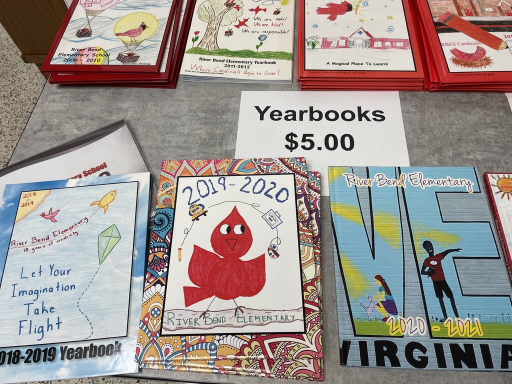 A table displays various books including yearbooks and flyers. A sign reads "Yearbooks $5.00." The books feature diverse artwork.