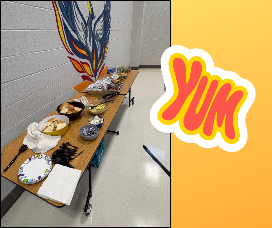 A room with a wall-mounted artwork, featuring a long table with various food items, utensils, plates, and napkins.