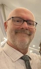 Dr. Wickline is pictured in selfie wearing a white shirt and tie. 