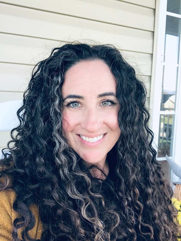 Ms. Winters is pictured sitting outside. She has long curly, black hair. 