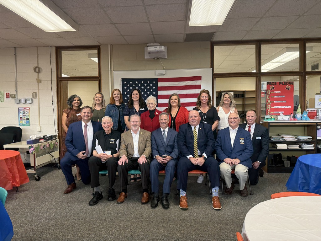 seven adults seated and standing in media center of school