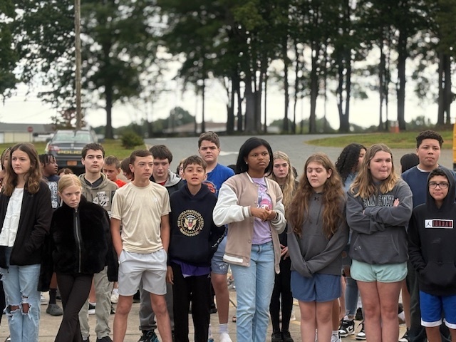 Various students gathered around the flagpole