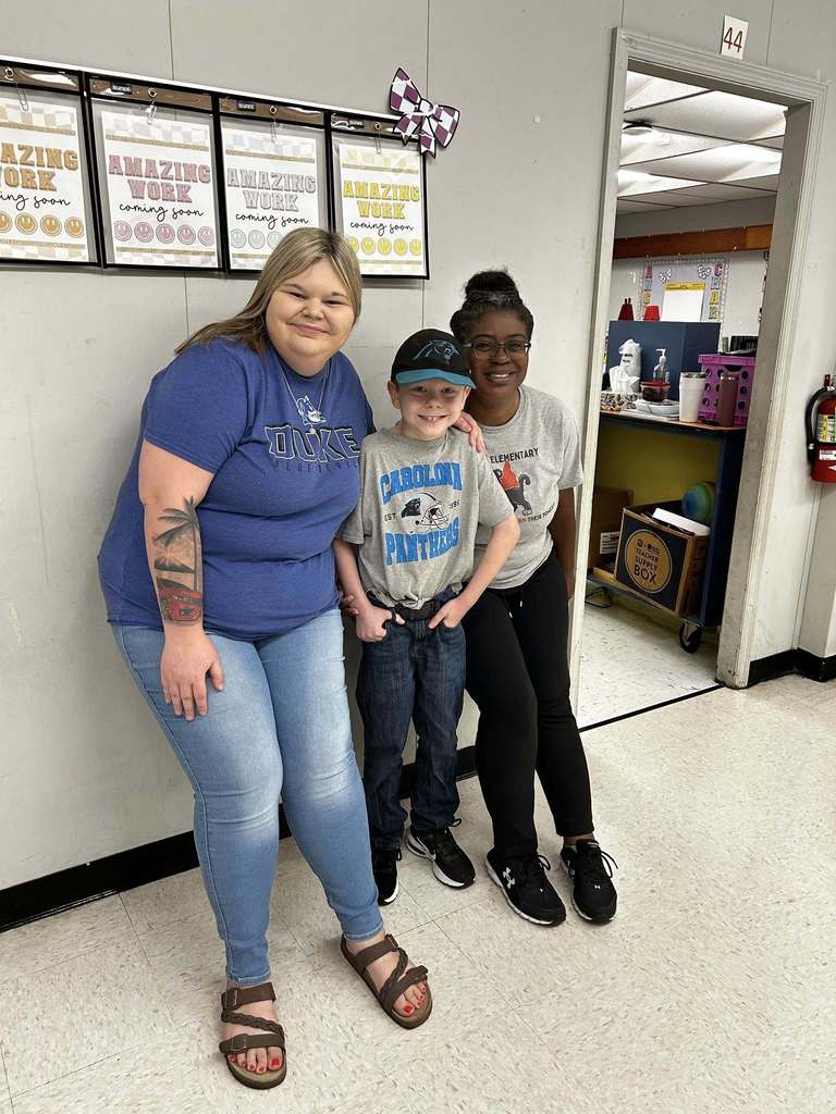 Two teachers stand with a student sporting their favorite team logos on their shirts.