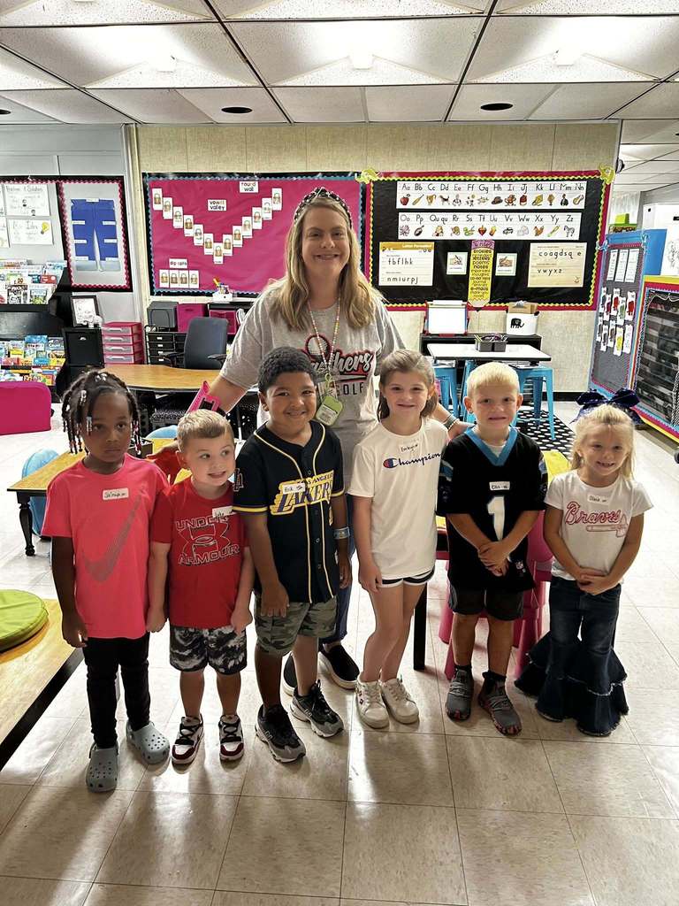 Six students stand with teacher sporting their favorite team logos on their shirts
