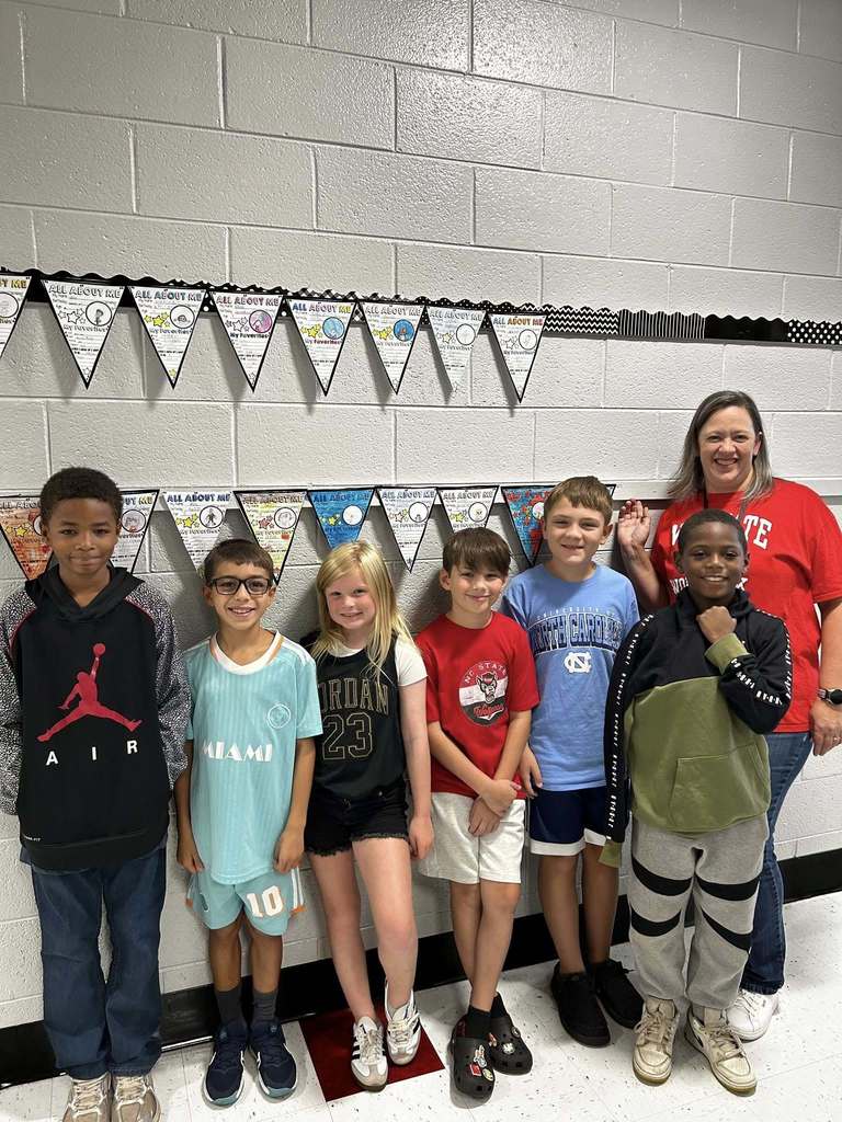 Six students stand with teacher sporting their favorite team logos on their shirts
