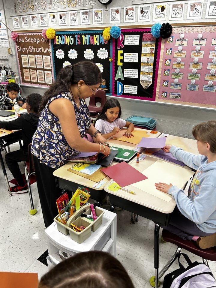 teacher helps a group of students at a table
