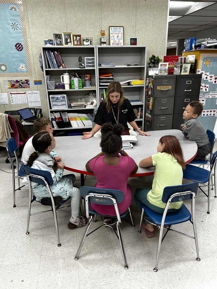 teacher teaching group of students at kidney shaped table