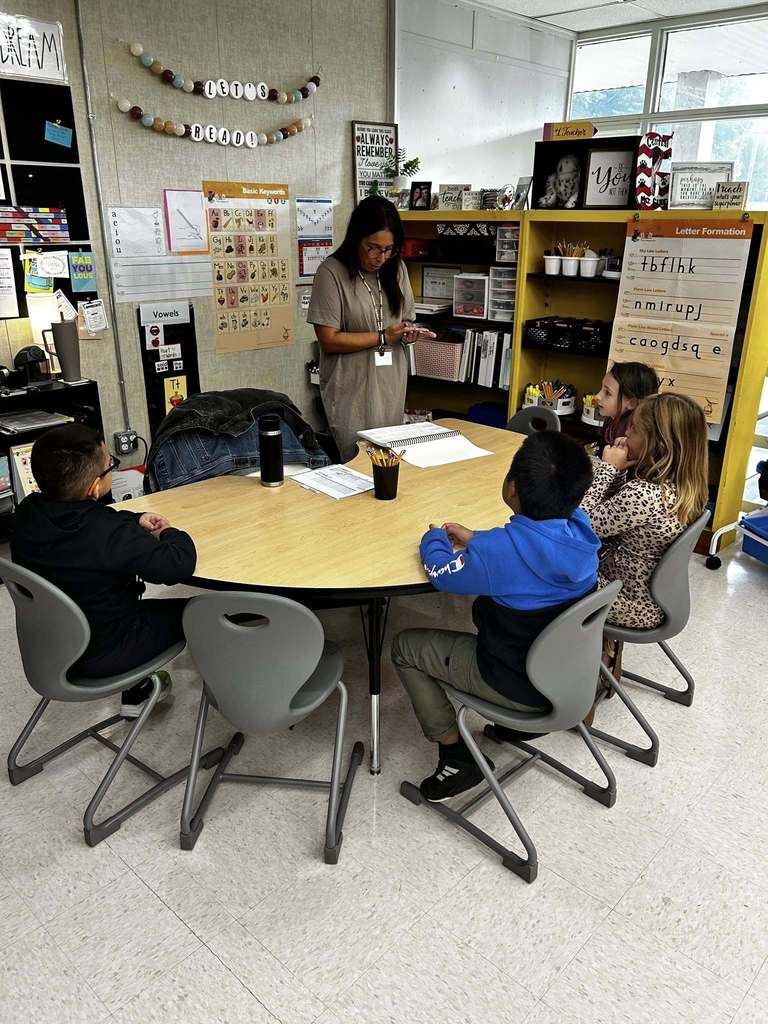 teacher teaching group of students at kidney shaped table