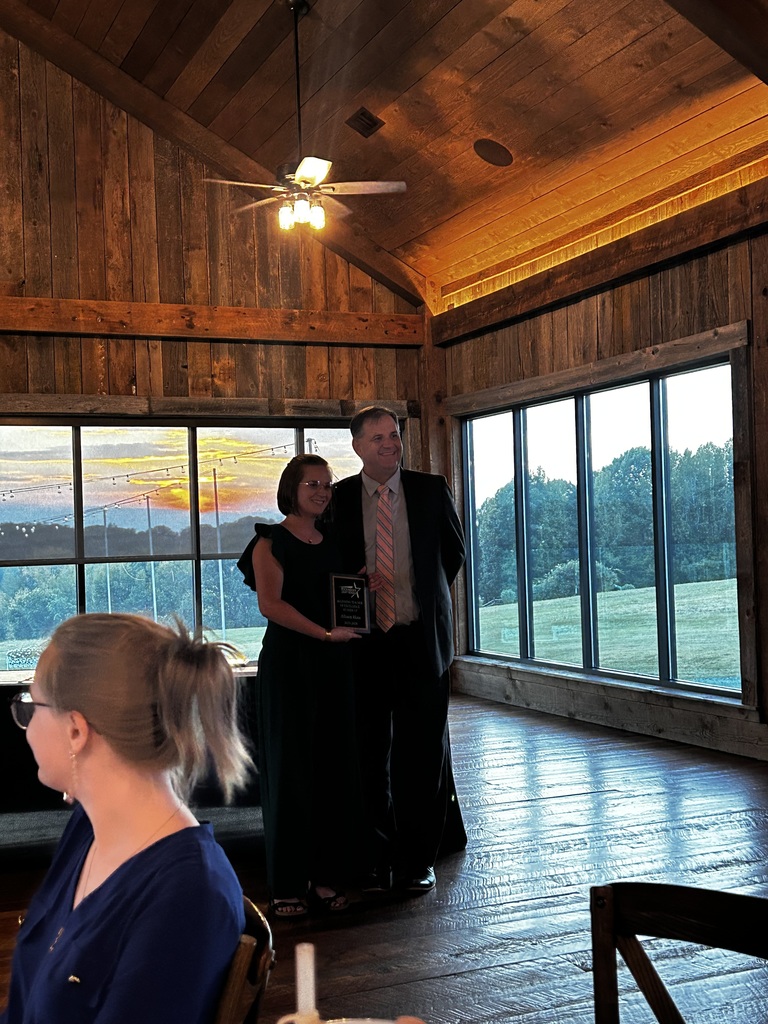 Ms. Allison Sigmon stands on the left side of Mr. Stover holding her Beginning Teacher of the Year plaque. 