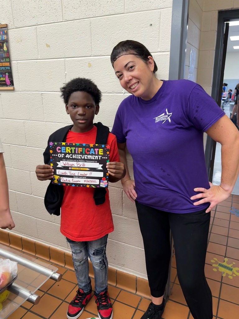 Lunch leader of the month stands with his certificate and the cafeteria manager
