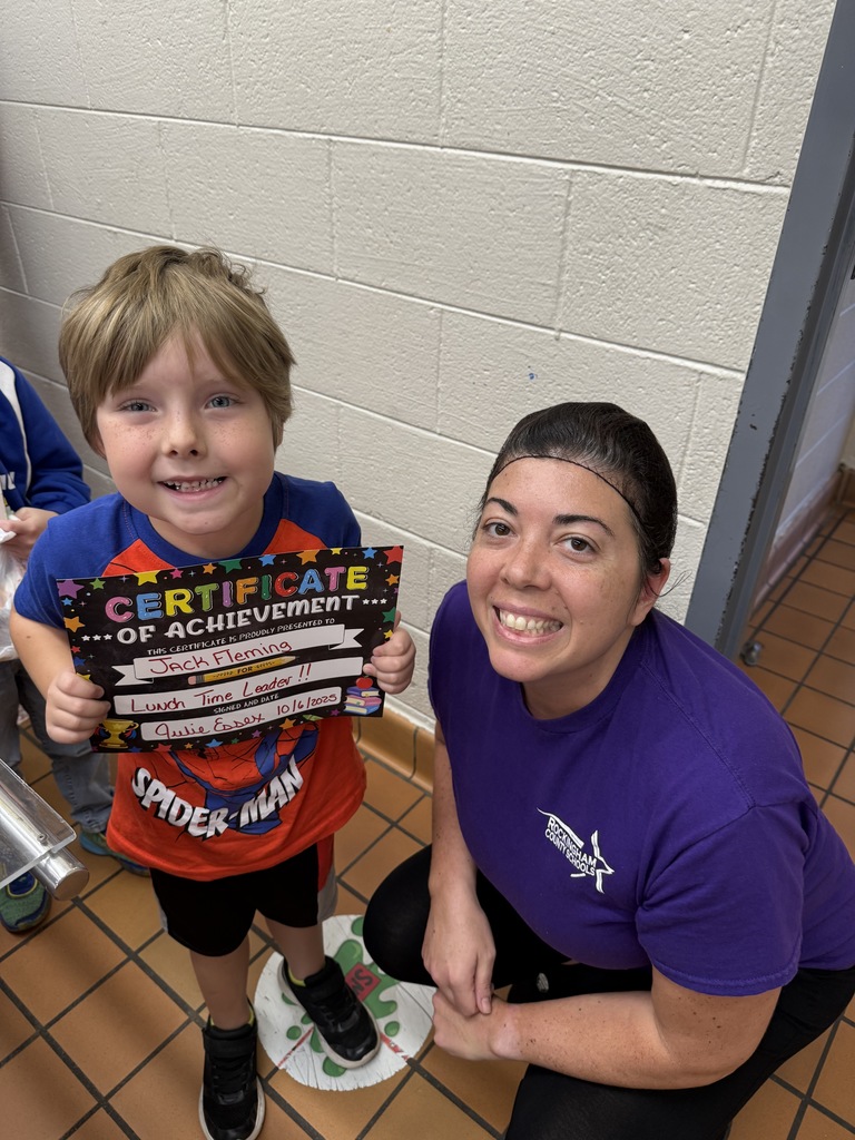 Lunch leader of the month stands with his certificate and the cafeteria manager