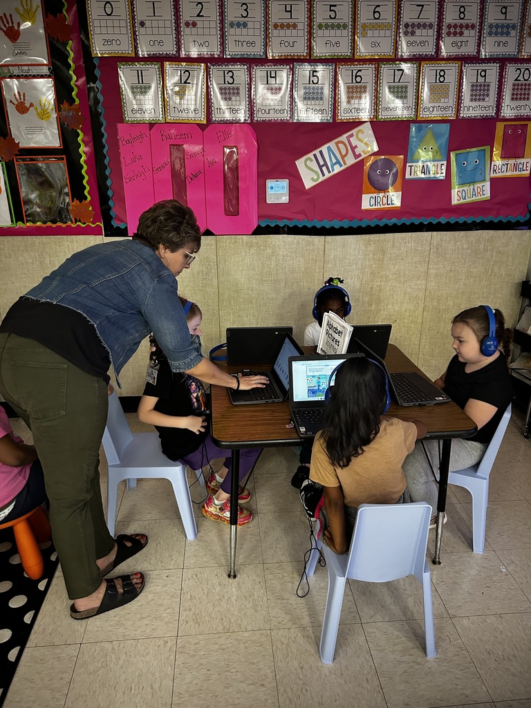Teacher works at square table with four students as they're on chromebooks